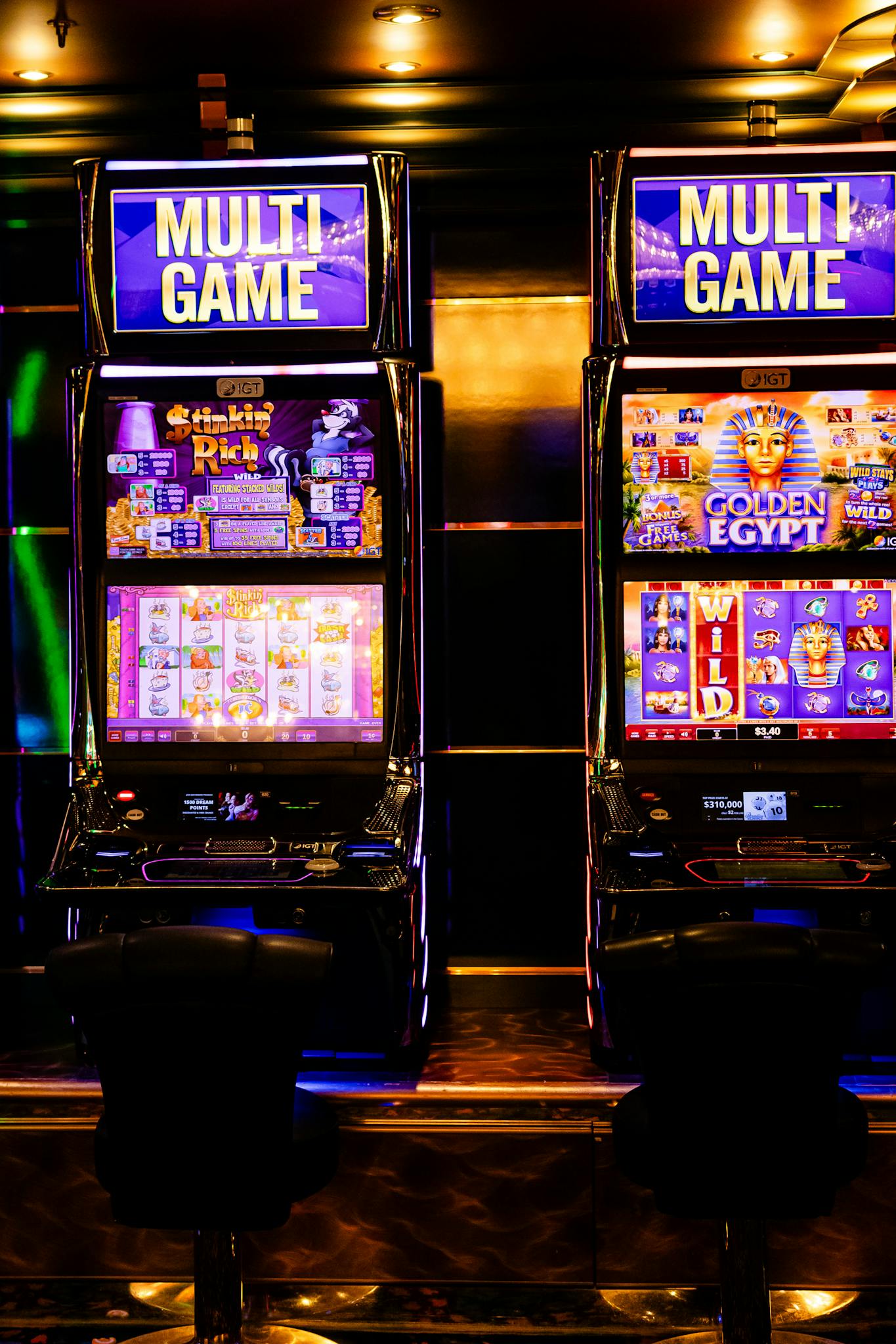 Colorful multi-game slot machines inside a lively casino environment at night.