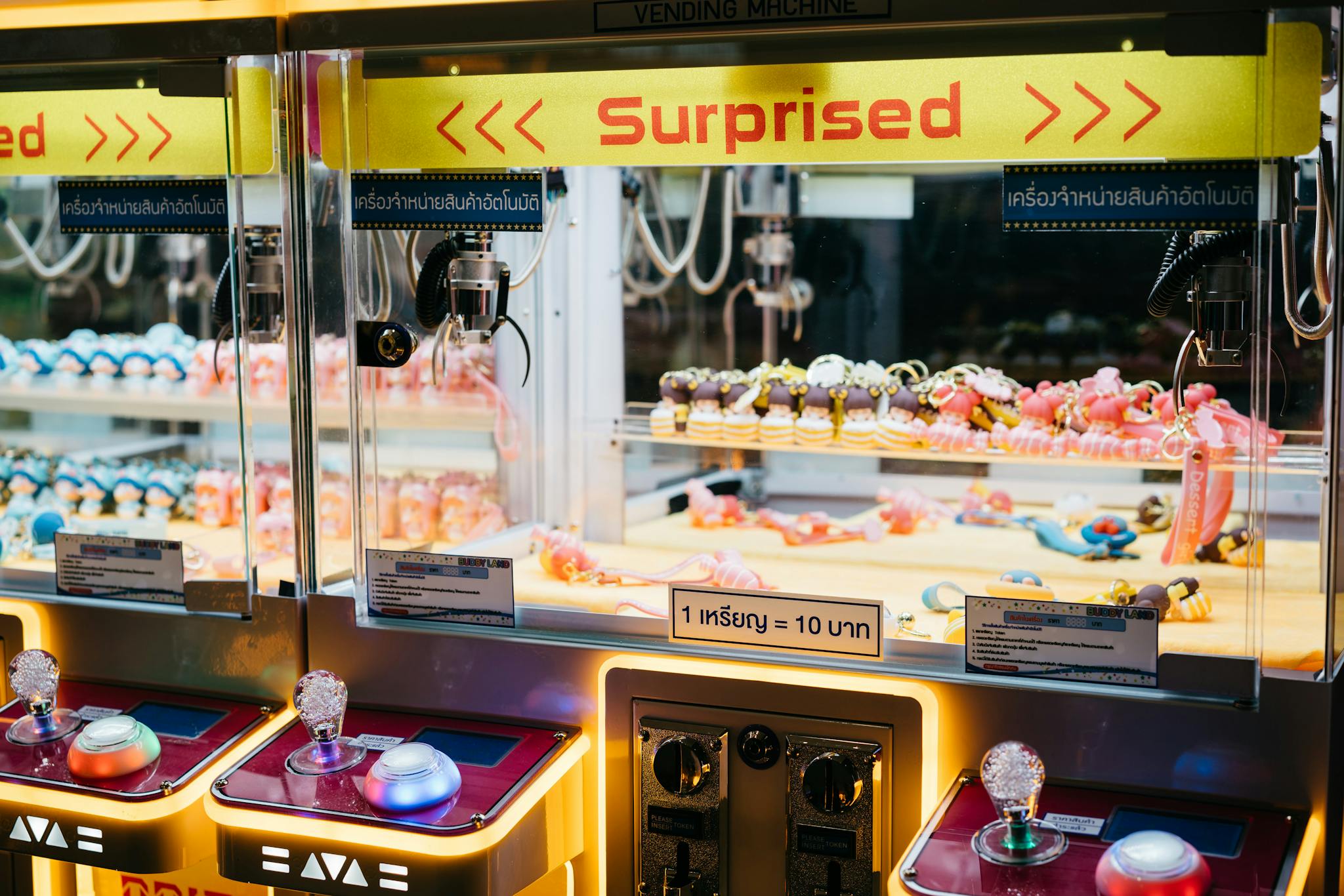 Colorful toys in an arcade claw machine labeled 'Surprised' with vibrant lighting.