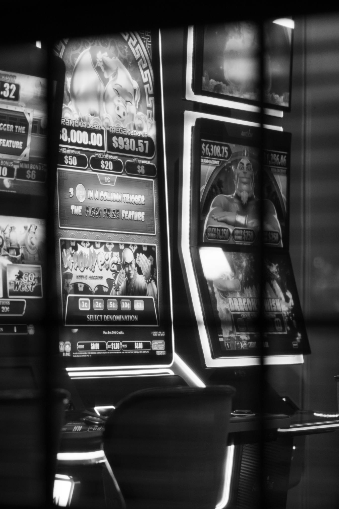 Monochrome image of casino slot machines reflecting lights.